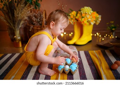 Baby With Easter Eggs In Yellow Jumpsuit. High Quality Photo