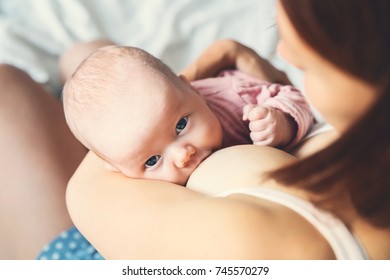 Baby eating mother's milk. Mother breastfeeding baby. Beautiful mom breast feeding her newborn child. Young woman nursing and feeding baby. Concept of lactation infant.