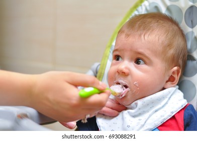 Baby eating with a spoon. Mom feeds the baby. Healthy food for my baby