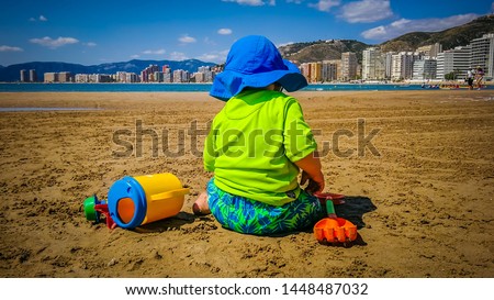 A baby enjoys summertime on the Racco beach of Cullera, which is a seaside town located in Valencia, Spain, Europe.
