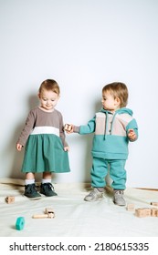 Baby Fashion. Unisex Gender Neutral Clothes For Babies. Two Cute Baby Girls In Neutral Color Palette Cotton Cloth