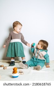 Baby Fashion. Unisex Gender Neutral Clothes For Babies. Two Cute Baby Girls In Neutral Color Palette Cotton Cloth