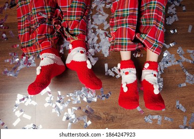 Baby Feet In Christmas Socks And Pajama Pants On Background Of Shiny Confetti. Winter Holiday Xmas And New Year Concept