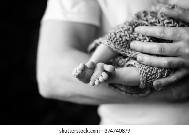 Baby feet in father hands. Black-and-white photo. Baby's feet in black and white
