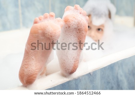 Baby feet in the foam in the bath. Hygiene, cleanliness concept.