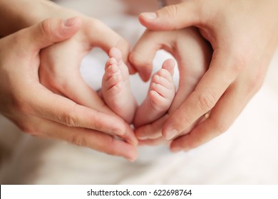 Сердце детских ножек: ножки ребенка в руках мамы и папы