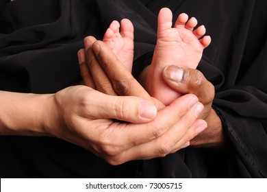 Baby feet held by mother and father's hands.