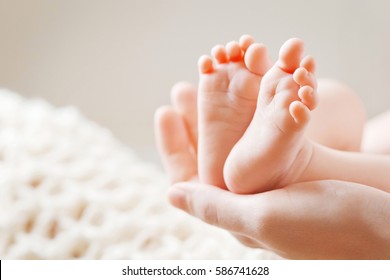 Детские ножки в руках матери. Мама и ее ребенок. Концепция счастливой семьи. Красивый концептуальный образ материнства