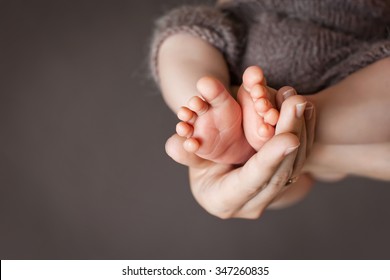 Babyfüße in den Händen der Mutter. Die Füße des kleinen Neugeborenen auf die weibliche Gestapfte Hände, Nahaufnahme. Mama und ihr Kind. Fröhliches Familienkonzept. Schönes konzeptuelles Bild der Mutterschaft