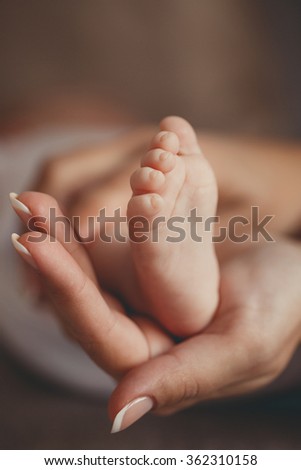 Baby feet in mother hands. Tiny Newborn Baby's feet on female Heart Shaped hands closeup. Mom and her Child. Happy Family concept. Beautiful conceptual image of Maternity? newborn baby feet in hands