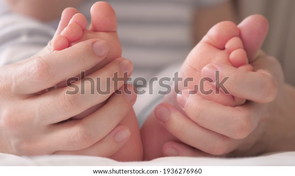 Baby feet in mother s hands. Feet of an infant,\
mom will embrace the baby with her arms. Happy Mother and her baby\
are playing together. Happy family concept. Childcare happy\
childhood. Family moments
