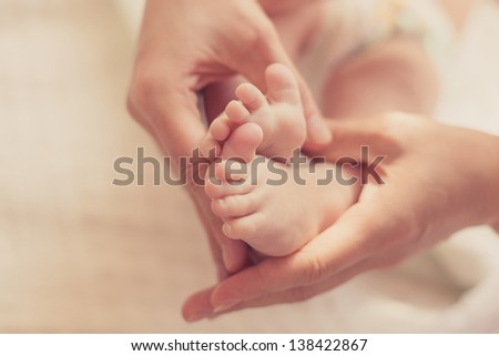 Baby feet in mother's hands closeup