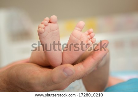 Baby feet in parent hands. Father and her child. Feet of newborn baby. Happy family and parenthood concept.