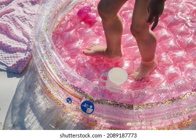 Baby Feet In The Pink Inflatable Pool.