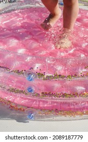 Baby Feet In The Pink Inflatable Pool.