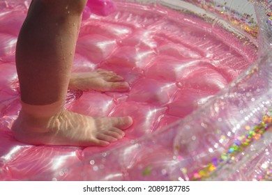 Baby Feet In The Pink Inflatable Pool.