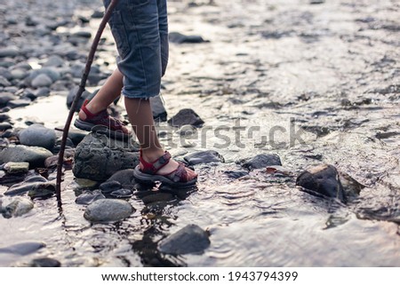 Baby feet in the stream. Game, building a dam. Happy childhood in nature. Crossing a mountain river to a ford. Little hiker tourist. Hiking with children. Legs Lifestyle