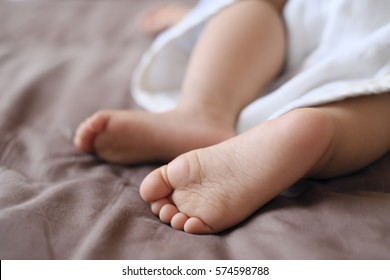 Baby feet taking a nap with brown sheets