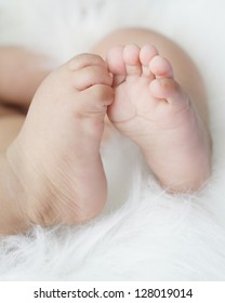 Baby Feet With Toes Curled Up, On White Fur Background