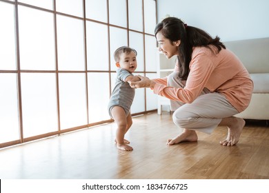 Baby First Step Walking. Mother Help Her Baby To Walk Her First Step At Home