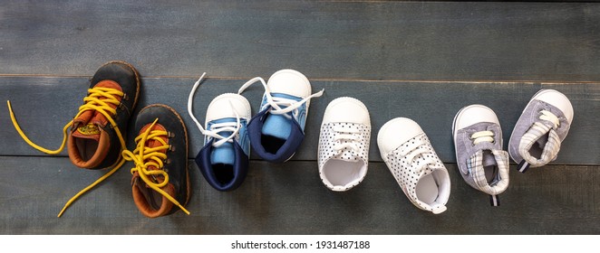 Baby First Steps. Four Pairs Of Boy Shoes Variety On Blue Color Wood Background, Top View. Kids Footwear, Booties And Soft Infant Shoes In A Row.