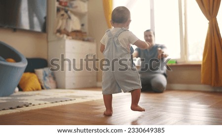 baby first steps. baby goes her father at window learns to walk to take first steps. happy family kid dream concept. dad calls son baby first steps indoors. happy family lifestyle indoors concept