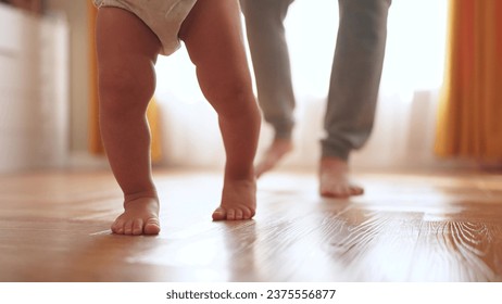 baby first steps. happy family kid dream concept. father teaches baby daughter to take first steps at home in front of window. lifestyle father's day concept. baby takes his first steps - Powered by Shutterstock