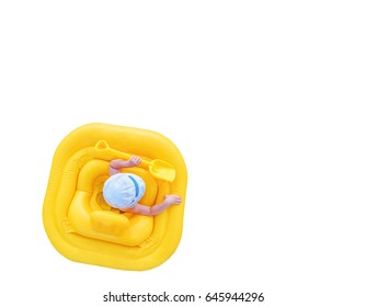 Baby floats in a yellow inflatable raft isolated on a white background. Small child with a shovel in yellow rubber ring, view from the top. Background with copy space.