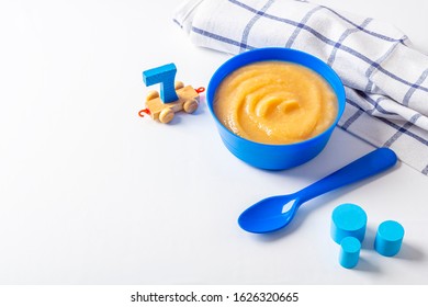 Baby Food. Fresh Homemade Applesauce. Blue Bowl With Fruit Puree On Fabric And Kids Toys On Table. The Concept Of Proper Nutrition And Healthy Eating. Organic And Vegetarian Food. Copy Space For Text