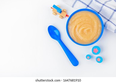 Baby Food. Fresh Homemade Applesauce. Blue Bowl With Fruit Puree On Fabric And Kids Toys On Table. The Concept Of Proper Nutrition And Healthy Eating. Organic And Vegetarian Food. Copy Space For Text