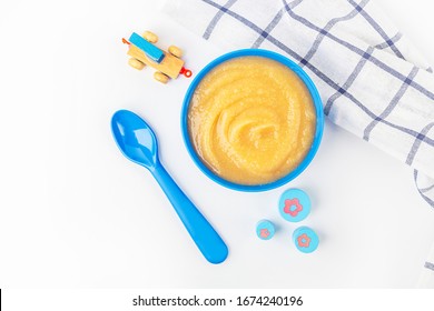 Baby Food. Fresh Homemade Applesauce. Blue Bowl With Fruit Puree On Fabric And Kids Toys On Table. The Concept Of Proper Nutrition And Healthy Eating. Organic And Vegetarian Food. Copy Space For Text