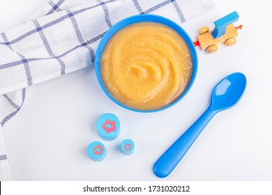 Baby Food. Fresh Homemade Applesauce. Blue Bowl With Fruit Puree On Fabric And Kids Toys On Table. The Concept Of Proper Nutrition And Healthy Eating. Organic And Vegetarian Food. Flat Lay