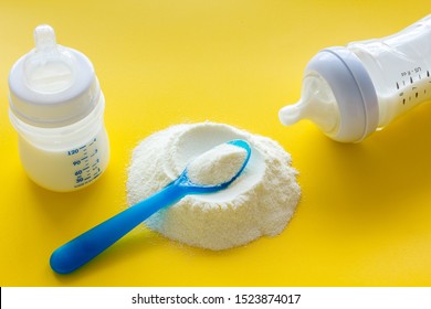 Baby Food. Powder In Spoon Near Baby Bottle On Yellow Background