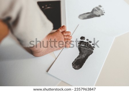 Baby footprints on white paper. Black footprint. The process of creating a baby footprint.
