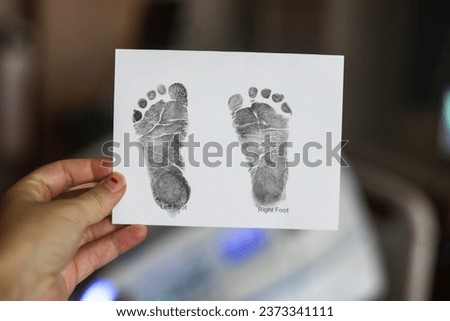 Baby footprints are visible on a sheet of paper in a hospital; the footprints were created using non-toxic ink designed for babies. 