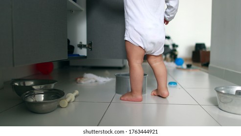 
Baby Getting Up From The Kitchen Floor. Baby Playing With Kitchen Utilities, Opening Closet. Toddler At Play With Pots And Pans