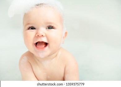 A Baby girl bathes in a bath with foam and soap bubbles - Shutterstock ID 1359375779
