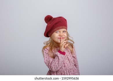 Baby Girl In Beret Shows Quietly Isolated On Grey Background