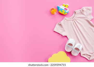 Baby girl bodysuit with toys and accessories, flat lay.