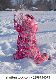 Baby Girl In Colorful Snowsuit Playing In Snow