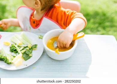 Baby Girl Eating Her Lunch In The Garden Outside In Summer