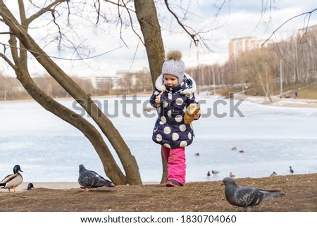 baby girl feeding the wild prince with bread in winter