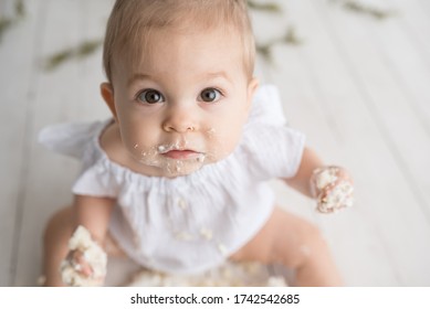 Baby girl first birthday cake smash on a white wood set in a white background and white cake