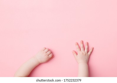 Baby Girl Hands On Light Pink Table Background. Pastel Color. Closeup. Point Of View Shot.