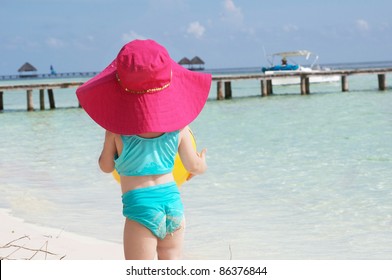 A Baby Girl In Her Sun Hat On The Beach