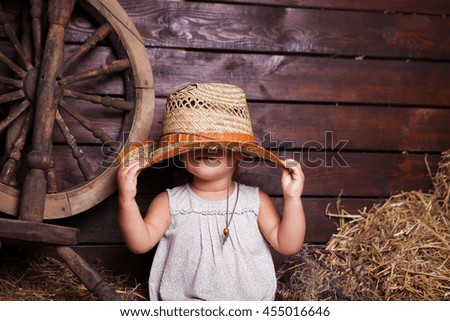 baby girl hiding under a straw hat