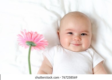 Baby girl holding a flower on her bed