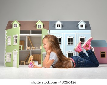 Baby Girl Kid Playing With Doll House Stuffed With Mini Furniture Toys And Doll Lying On A Floor In Play Room At Home Or Kindergarten 