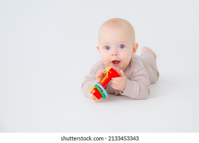 baby girl is lying playing with a rattle on a white background studio shooting