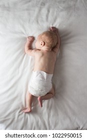 Baby Girl In A Nappy Lying On A Belly On A White Blanket. White Background. Flat Lay, Top View.